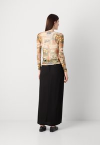 Long-sleeve sheer top with a multicolor vintage postcard print, paired with a black maxi skirt and black flats. Textured pattern throughout.