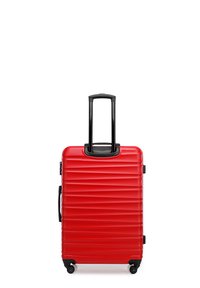 Valise rigide rouge avec texture rainurée, poignee rétractable noire, poignee latérale et quatre roues pour la mobilité.