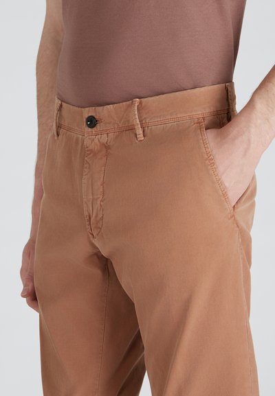 Brązowe bawełniane spodnie z teksturowanym wykończeniem, z bocznymi kieszeniami i pojedynczym zapięciem na guzik w pasie. Dopasowany krój i miękka tkanina.