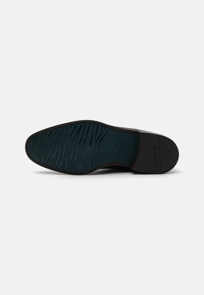 Sole di scarpa nera con rivestimento in gomma texturizzata, caratterizzata da un bordo liscio e una leggera curvatura sul tallone per una maggiore aderenza.