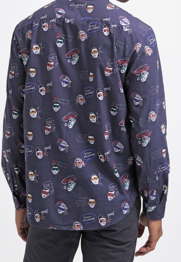 Camicia in tessuto scuro con volti astratti colorati e motivi testuali, maniche lunghe, design con bottoni e orlo arrotondato.