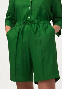 Pantaloni corti verdi brillanti realizzati in tessuto leggero, con una vita elastica e un laccio, tasche laterali e un fit rilassato.
