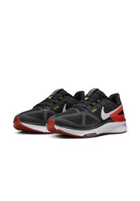 Zapatillas deportivas negras con un upper de malla texturizada, logo Swoosh blanco, acentos verdes, soporte para el talón rojo y una media suela blanca.