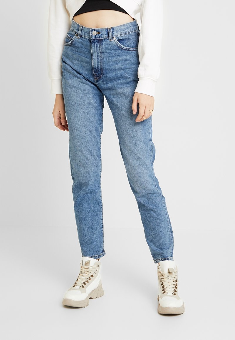 Ljusblå högmidjade jeans med rak passform, tillverkade av denim, kombinerade med krämfärgade snörstövlar med en kraftig sula.