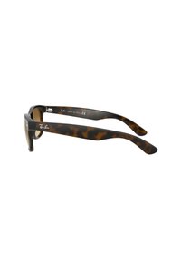Occhiali da sole tartarugati con montatura spessa, lenti marrone sfumate e aste nere con il logo Ray-Ban. Fabbricati in Italia.