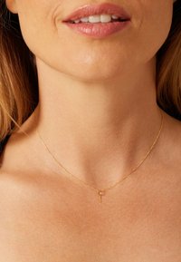 Gold chain necklace featuring a delicate key pendant, with a smooth, refined texture and minimalistic design.