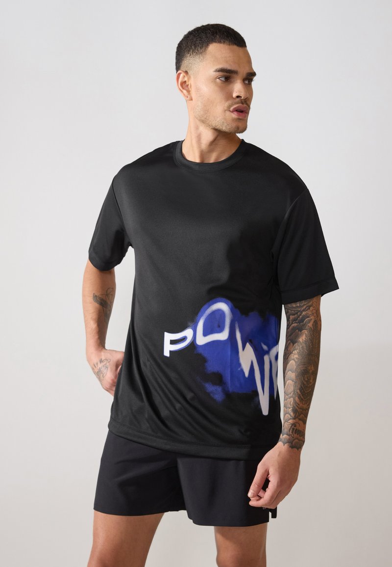 Schwarzes Sport-T-Shirt mit glatter Textur, das ein blau-weißes Grafikdesign mit der Aufschrift "POWER" auf der Vorderseite zeigt. Kombiniert mit schwarzen Shorts.