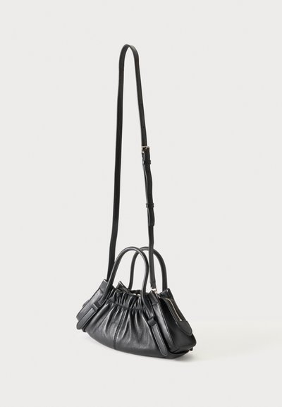 Sac à main en cuir noir avec design plissé, deux poignées supérieures, bandoulière longue réglable et poche latérale zippée sur fond blanc.