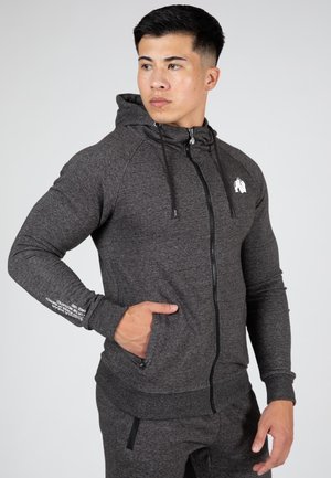 Donkergrijze zip-up hoodie met een voorkruik, verstelbare trekkoorden en geribde manchetten. Logo op de borst en tekst op de mouw.