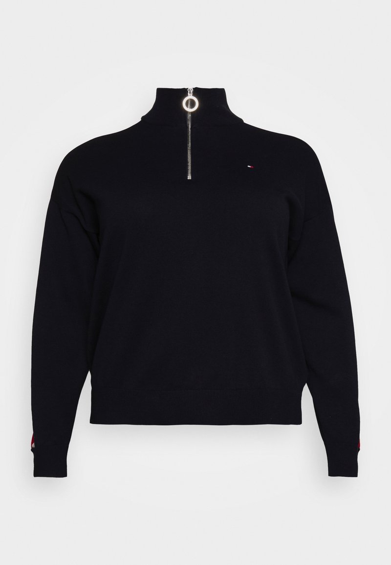 Pull-over noir avec col montant et fermeture éclair argentée à quart de tour. Il présente un petit logo sur la poitrine et des poignets côtelés.