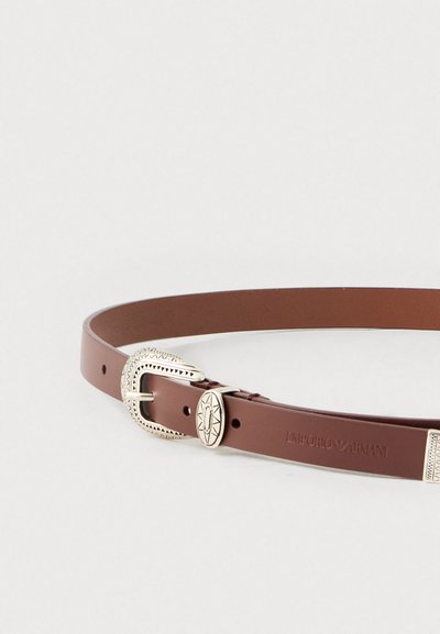Καφέ δερμάτινη ζώνη με ασημί αγκράφα με σχέδιο και χαραγμένο λογότυπο. Διαθέτει πολλαπλές τρύπες για ρυθμιζόμενο μέγεθος.