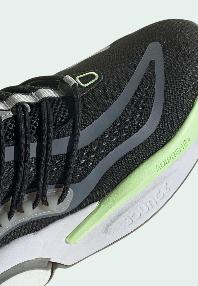 Basket noir avec un dessus en maille, des accents gris et une semelle blanche avec des touches de vert, étiquetée "ADIPRENE" et "BOUNCE."
