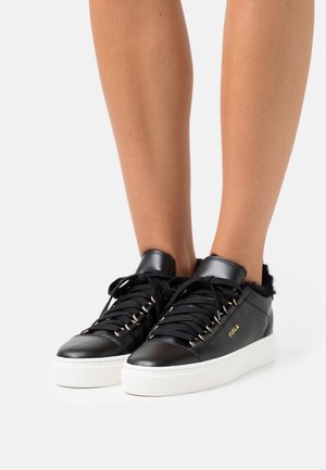 Zwarte leren sneaker met een witte rubberen buitenzool, zacht interieur, goudkleurige oogjes en zwarte veters. Bevat het merkembleem aan de zijkant.