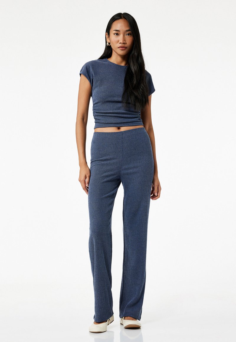 To-delt navy-blå outfit med en tætsiddende, kortærmet top og lige bukser. Stoffet har et struktureret, ribbet design.