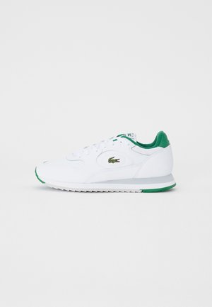 White sneakers with green accents, smooth leather upper, lace-up closure, padded collar, and textured rubber sole with green detailing.