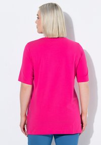 Camiseta fucsia de corte holgado, con mangas cortas y escote redondeado; textura suave sin patrones ni acentos visibles.