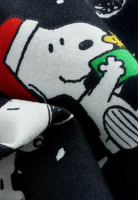 Czarna tkanina z postaciami z kreskówek. Szczególne detale to Snoopy trzymający zielony przedmiot oraz czerwony akcent w tle.