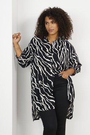 Black and white zebra-patterned button-up shirt made of lightweight fabric, featuring a relaxed fit, long sleeves, and a high-low hem.