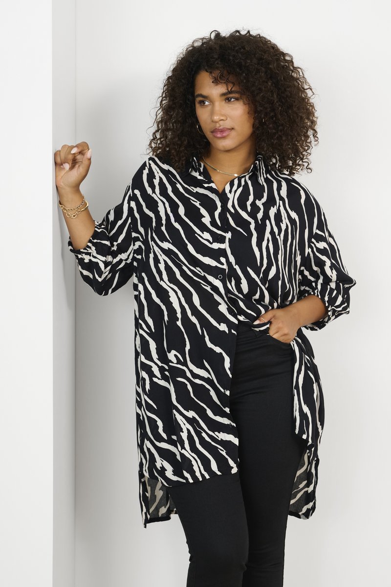 Chemise à boutons à motif zèbre noir et blanc en tissu léger, avec une coupe décontractée, des manches longues et un ourlet asymétrique.