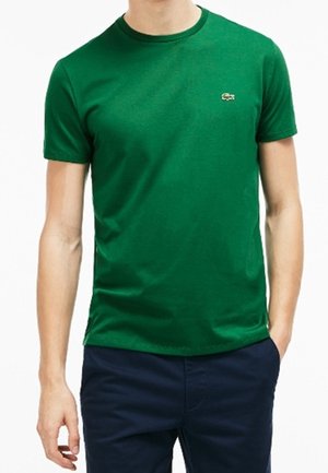 Vihreä, lyhythihainen t-paita, valmistettu puuvillasta. Pyöreä kaula-aukko ja pieni logo rinnassa. Sileä pinta ja tavallinen istuvuus.