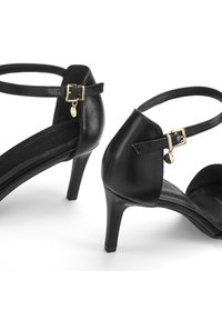 Black heeled sandals with a smooth leather finish, adjustable ankle straps featuring gold buckles, and a subtle logo tag on the side.