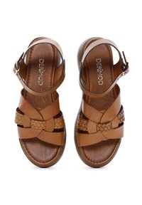 Sandalias de cuero marrón con un diseño de tiras trenzadas, correa adjustable en el tobillo, suela plana y plantilla acolchada para mayor comodidad.