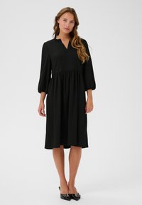 Black midi dress with a V-neck, gathered waistline, and balloon sleeves. Made of lightweight fabric with a smooth texture.