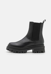 Bottines en cuir noir avec des panneaux latéraux élastiques, bout rond et semelle en caoutchouc épaisse dotée de profondes rainures pour une meilleure adhérence.