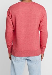 Rotes Sweatshirt aus Baumwolle mit Rundhalsausschnitt, langen Ärmeln sowie gerippten Bündchen am Saum und an den Ärmeln, mit einer weichen, strukturierten Oberfläche.