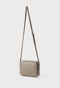 Borsa a tracolla in pelle grigia con superficie texturizzata, chiusura a zip e tracolla regolabile. Forma rettangolare compatta con dettagli minimali.