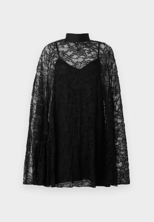Top in pizzo nero con maniche lunghe e fluide, dotato di un collo alto e un design a strati. Complessi motivi floreali arricchiscono il tessuto trasparente.