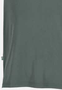 Donkergroene mesh t-shirt met een zachte textuur, voorzien van kleine perforaties, korte mouwen en een blauw-gele label aan de zoom.