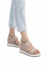 Sandali con zeppa intrecciata beige, dotati di due ampie cinghie, hardware regolabile e suola bianca. Superficie testurizzata e soletta morbida visibili.
