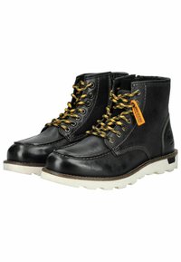 Botas de tobillo de cuero negro con cordones amarillos, suela de goma blanca y costuras en contraste; cuenta con una etiqueta en el lateral.