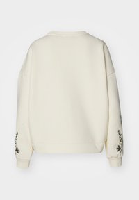 Sudadera de color crema con mangas anchas y relajadas, adornada con diseños florales bordados en ambas mangas. Tejido suave con cuello redondo.