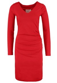 Robe rouge à manches longues, longueur genou, avec col en V et détails froncés sur les côtés, silhouette ajustée et texture de tissu lisse.