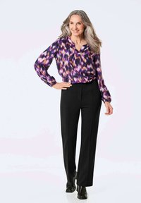 Paarse en roze gebloemde blouse met een V-hals, lange mouwen; gecombineerd met rechte zwarte broek en zwarte enkellaarzen.