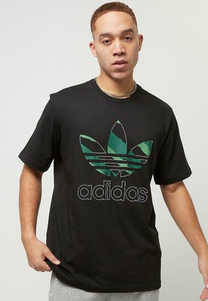 Sort crew-neck t-shirt lavet af bomuld, prydet med et stort grønt og sort camouflage Adidas trefoil-logo og fed "adidas" skrift i hvid.