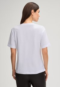 Witte katoenen t-shirt met een ronde halslijn en korte mouwen, met een relaxte pasvorm en een rechte zoom. Gladde textuur.