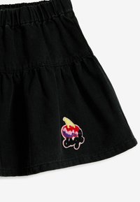 Falda de mezclilla negra con cinturilla elástica, que presenta un diseño en capas y un colorido parche bordado de helado en la parte frontal.