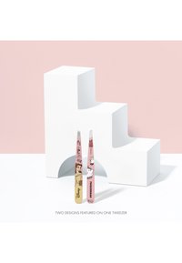 Rosa och gula Disney-tema pincetter med karaktärerna Belle och Mrs. Potts, stående framför en vit geometrisk rekvisita på en rosa bakgrund.