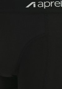 Black fitted underwear made of stretchy fabric with a wide waistband featuring white "aprel" branding and reinforced stitching details.