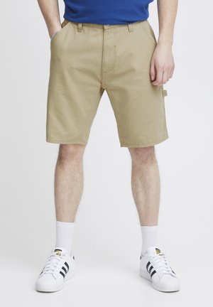 Khaki shorts lavet af letvægtsstof, med flad front, bæltesløjfer og sidelommer. Kombinationen med hvide sokker og sneakers.