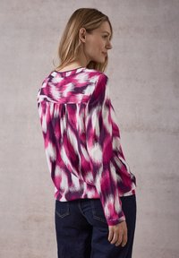 Blusa a maniche lunghe con un vivace motivo rosa, bianco e viola. Tessuto leggero con una vestibilità comoda e dettaglio plissettato sulla schiena.