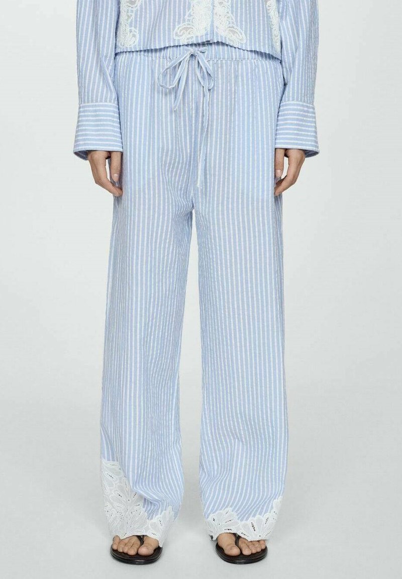 Lichtblauwe en witte gestreepte pyjamabroek met een tailleband met trekkoord, wijde benen en witte kantafwerking aan de onderkant. Katoenen materiaal.