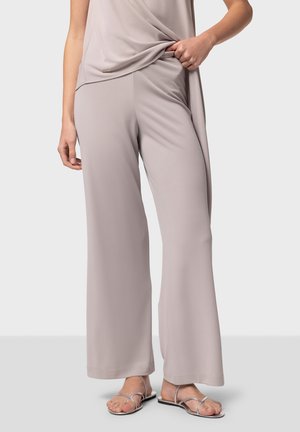 Lichtgrijze wijde broek gemaakt van een gladde stof met een vloeiende uitstraling. Gecombineerd met strap sandalen in zilver, wat een minimalistische stijl laat zien.