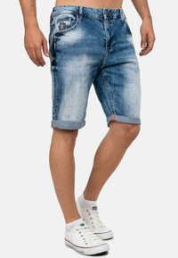 Shorts en denim bleu clair avec un effet délavé. Ourlet à revers et poches avant. Associés à des baskets blanches pour un look décontracté.