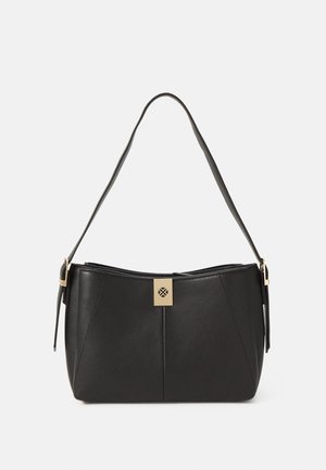 Czarna skórzana torba na ramię z regulowanym paskiem i złotym kwadratowym zapięciem z okrągłym wycięciem, na tle plain białego.