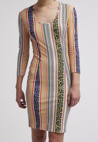 Långärmad kroppsnära klänning med ett flerfärgat randigt mönster och ormskinsaccent. Tillverkad av elastiskt material, med rundad halsringning.