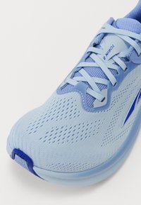 Chaussure de course bleu clair avec tige en maille, détails texturés et lacets à plat. Présente un accent bleu sur le côté et un design de bout arrondi.